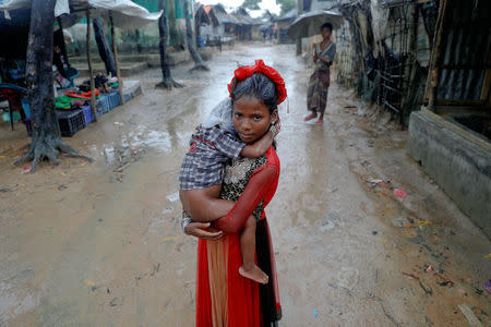 A Rohingya girl wearing her holiday dress carries a child through a refugee camp near Cox's Bazar, Bangladesh October 8, 2017. REUTERS/Damir Sagolj