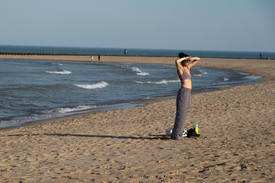 A woman stands on the beach as spring-like temperatures hit Chicago on Monday (Getty Images)