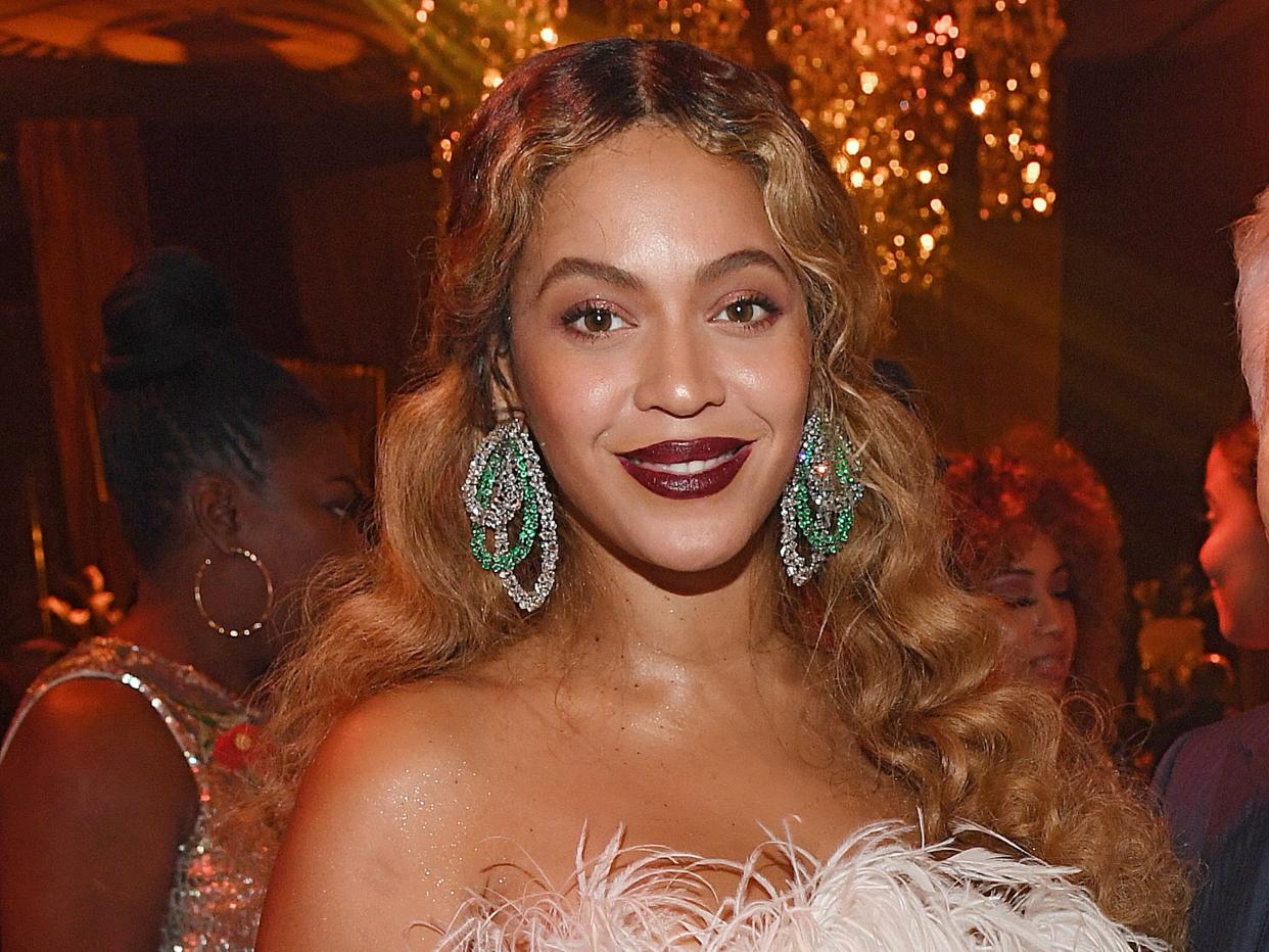 Beyoncé in a silver gown with feathers at the top and turquoise earrings