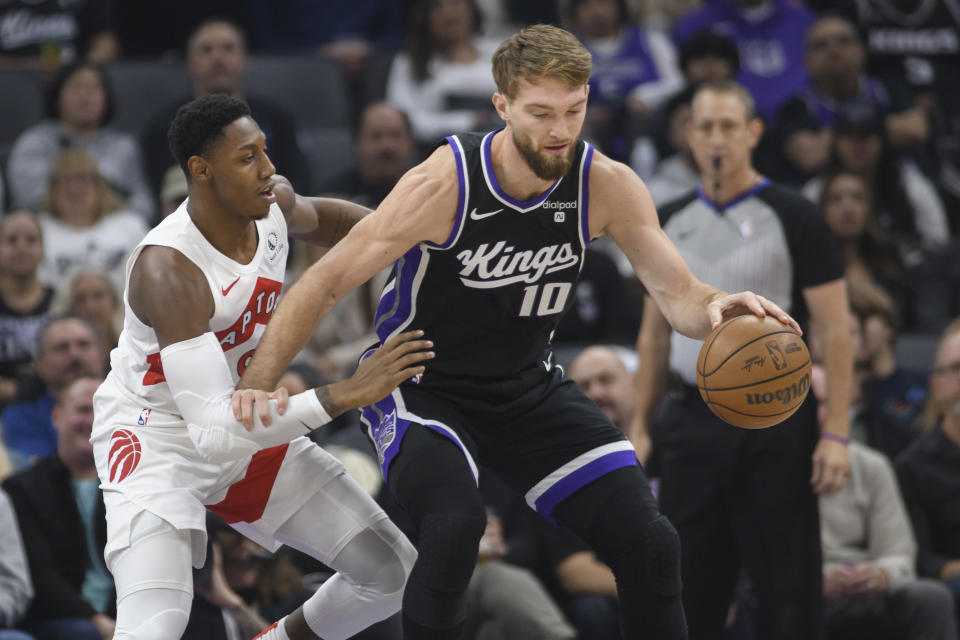 Toronto Raptors guard RJ Barrett, left, guards against Sacramento Kings forward Domantas Sabonis (10) during the first quarter of an NBA basketball game in Sacramento, Calif., Friday, Jan. 5, 2024. (AP Photo/Randall Benton)