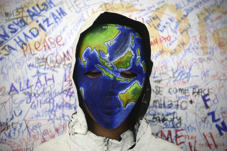 An unidentified woman with her face painted, depicting the flight of the missing Malaysia Airline, MH370, poses in front of the "wall of hope" at Kuala Lumpur International Airport in Sepang, Malaysia, Monday, March 17, 2014. Authorities now believe someone on board the Boeing 777 shut down part of the aircraft's messaging system about the same time the plane with 239 people on board disappeared from civilian radar. But an Inmarsat satellite was able to automatically connect with a portion of the messaging system that remained in operation, similar to a phone call that just rings because no one is on the other end to pick it up and provide information. No location information was exchanged, but the satellite continued to identify the plane once an hour for four to five hours after it disappeared from radar screens. (AP Photo/Joshua Paul)