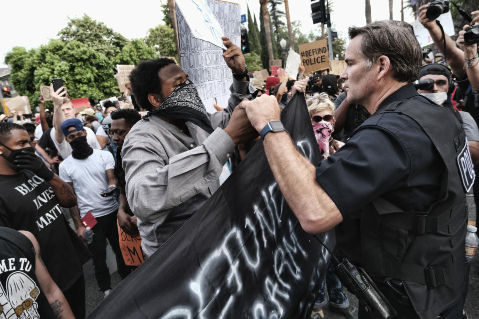 FILE - Los Angeles Captain Cory Palka, right reaches out and offers a handshake to a "Black Lives Matter" protester outside Los Angeles Mayor Garcetti's house in Los Angeles Tuesday, June 2, 2020. CBS and its former president, Leslie Moonves, will pay $30.5 million as part of an agreement with the New York attorney general's office, which says the network's executives conspired with a Los Angeles police captain later identified as Palka to conceal sexual assault allegations against Moonves. (AP Photo/Richard Vogel, File) . (AP Photo/Richard Vogel, File)