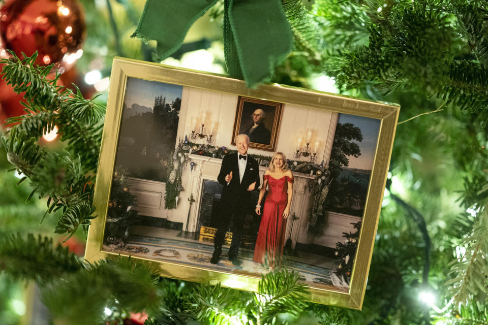 FILE - A photo of President Joe Biden and first lady Jill Biden sits in a Christmas tree in the State Dining Room of the White House during a press preview of the White House holiday decorations, Nov. 29, 2021, in Washington. In pre-pandemic times, presidents and first ladies spent many evenings in December before Christmas hosting nearly two dozen holiday parties and receptions, sometimes two per day, where they stood in line for hours to pose for photos with ecstatic guests. (AP Photo/Evan Vucci, File)