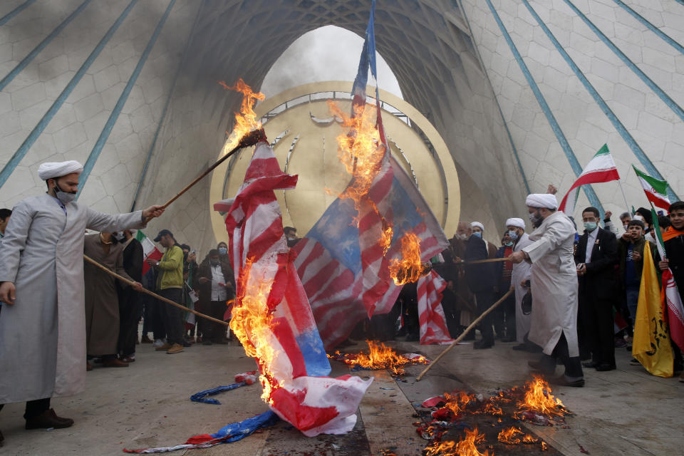 Clerics burn representations of the U.S. flag under the Azadi (freedom) monument tower during the annual rally commemorating the anniversary of Iran's 1979 Islamic Revolution, in Tehran, Iran, Friday, Feb. 11, 2022. Thousands of cars and motorbikes paraded in the celebration, although fewer pedestrians were out for a second straight year due to concerns over the coronavirus pandemic. (AP Photo/Vahid Salemi)