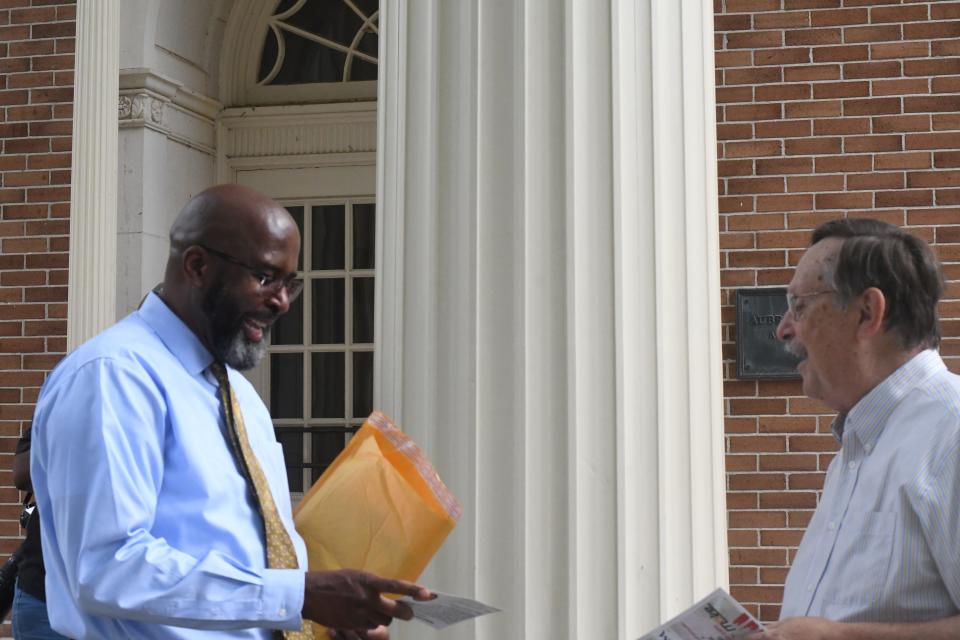 University of Southern Mississippi President Rodney Bennett, left, looks over a petition card as he talks with former provost Professor Denis Wiesenberg outside the university's administration building, Thursday, May 5, 2022, in Hattiesburg, Miss. A folder with over 300 petition cards demanding higher wages for university employees was delivered to Bennett, who told the group, "I have my packet. I have my materials. We have a lot of work to do."