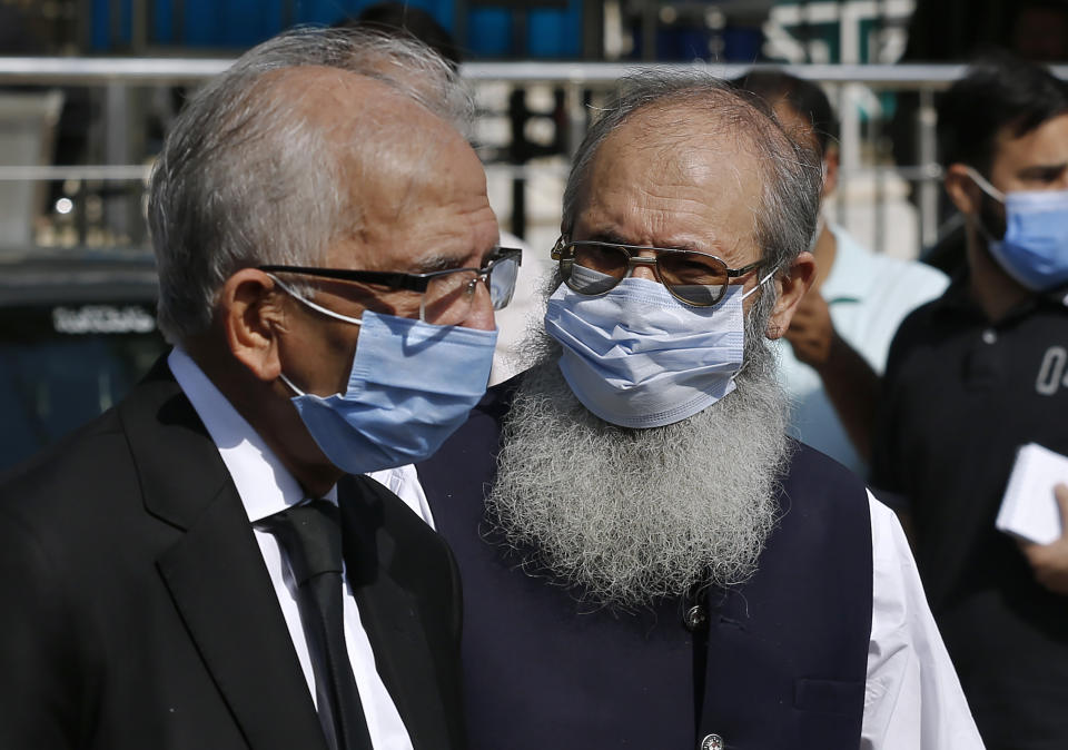 Ahmed Saeed Sheikh, right, father of a British-born militant Ahmed Omar Saeed Sheikh, leaves the Supreme Court with his lawyer Mahmood Ahmed Sheikh, left, after an appeal hearing in the Daniel Pearl case, in Islamabad, Pakistan, Wednesday, Oct. 7, 2020. Ahmed Omar Saeed Sheikh, who has been on death row over the 2002 killing of U.S. journalist Daniel Pearl, will remain in jail for another three months under a government order, a prosecutor told the country's top court Wednesday as it took up appeals of Pearl’s family and government against acquittal of all accused of murder charges by another court. (AP Photo/Anjum Naveed)