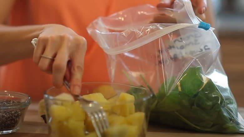 putting fruit and greens into freezer bag