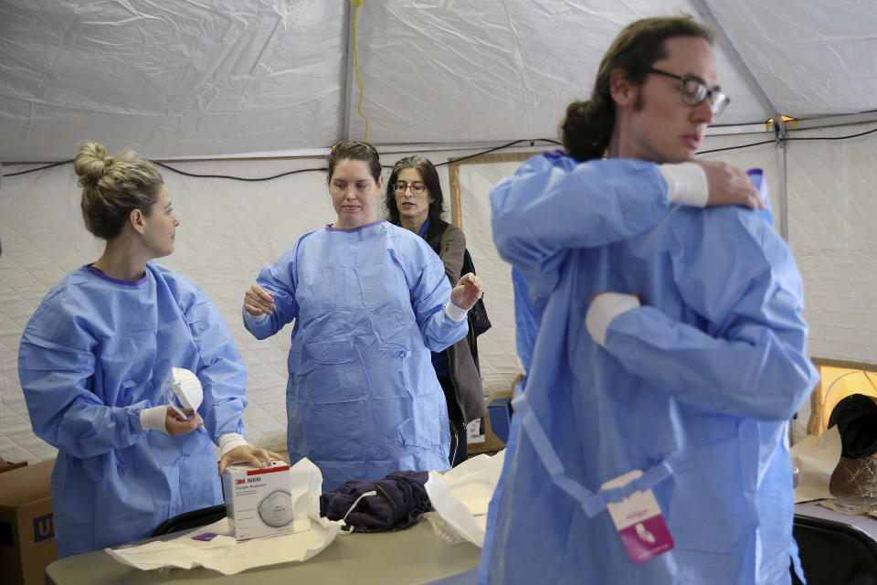 Philadelphia Medical Reserve Corps volunteers, from left, Marina Spitkovskaya, Megan Boyle, and Stephen Bonett , all of whom are nurses, put on their protective outfits with the help of Dr. Felicia Lewis, a Philadelphia Department of Public Health medical epidemiologist, as the city's coronavirus testing site prepared to open next to Citizens Bank Park in South Philadelphia on Friday, March 20, 2020. The site, which opened Friday afternoon, is the first city-run location where people can be swabbed to determine if they have the coronavirus. At the time of opening, it was only for people with symptoms who are over 50 and healthcare workers with symptoms.(Tim Tai/The Philadelphia Inquirer via AP)