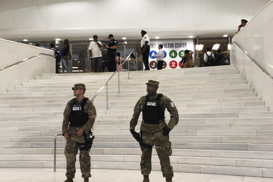 Law enforcement stand in front of a New York City Subway entrance at the Oculus transportation hub after reports of a suspicious package on a subway platform in New York on Friday, Aug. 16, 2019. Police say two suspicious objects that prompted an evacuation of the major lower Manhattan subway station are not explosives. New York Police Department Counterterrorism Chief James Waters tweeted Friday that the bomb squad cleared the items found at the Fulton Street station. The station is a busy transit hub a few blocks from the World Trade Center. (AP Photo/Joe Danborn)