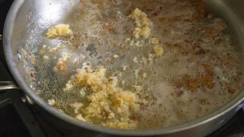 garlic cooking in a metal skillet