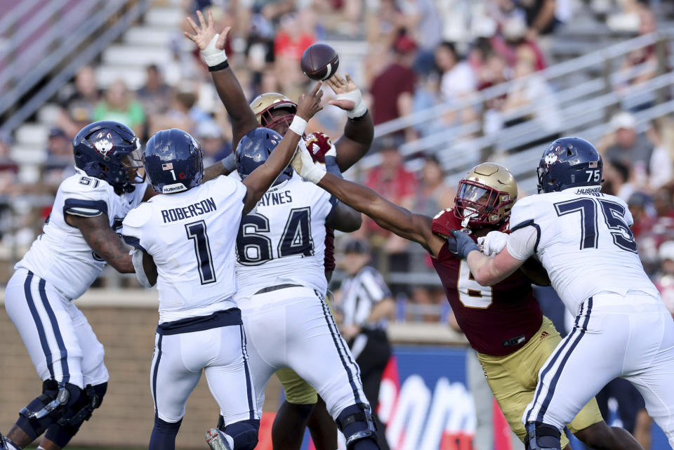 UConn quarterback Ta'Ruan Roberson (1) releases the ball as Boston College defensive end Donovan Ezeiruaku (6) closes in during the second half of an NCAA college football game Saturday, Oct. 28, 2023 in Boston. (AP Photo/Mark Stockwell)