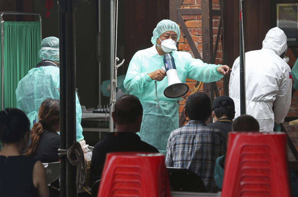 Medical personnel wearing protective gear, guide people at a rapid coronavirus testing center after the infection alert rose to level 3 in Taipei, Taiwan, Tuesday, May 18, 2021. (AP Photo/Chiang Ying-ying)