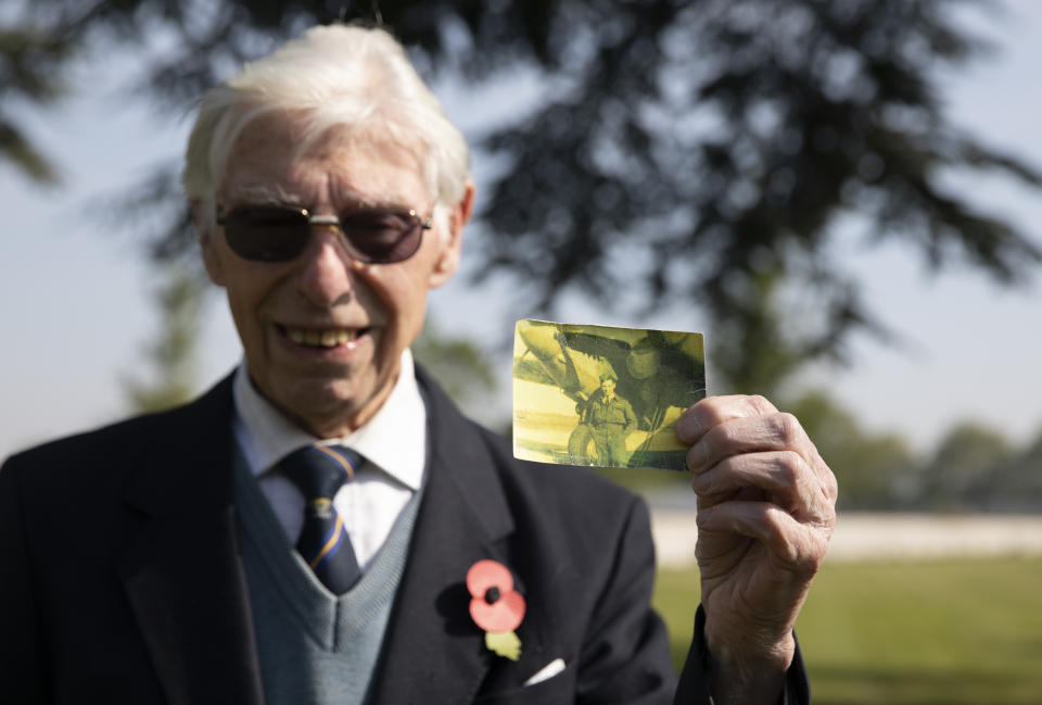 British RAF veteran George Sutherland, 98, holds up a photo of himself as a World War II aircraft mechanic as he poses at Lijssenthoek war cemetery before taking part in a VE Day charity walk to raise funds for Talbot House in Poperinge, Belgium, Friday, May 8, 2020. Sutherland's segment walked from the Lijssenthoek war cemetery to Talbot house to raise money for the club which is currently closed due to coronavirus lockdown regulations. The club, founded in 1915 was a place for British soldiers to rest during both the First and Second World Wars. (AP Photo/Virginia Mayo)