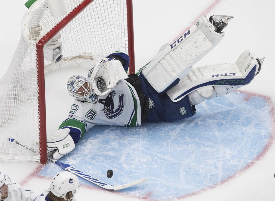 Vancouver Canucks' goalie Jacob Markstrom (25) dives at the puck against the St. Louis Blues during overtime in an NHL hockey Stanley Cup first-round playoff series, Friday, Aug. 14, 2020, in Edmonton, Alberta. (Jason Franson/The Canadian Press via AP)