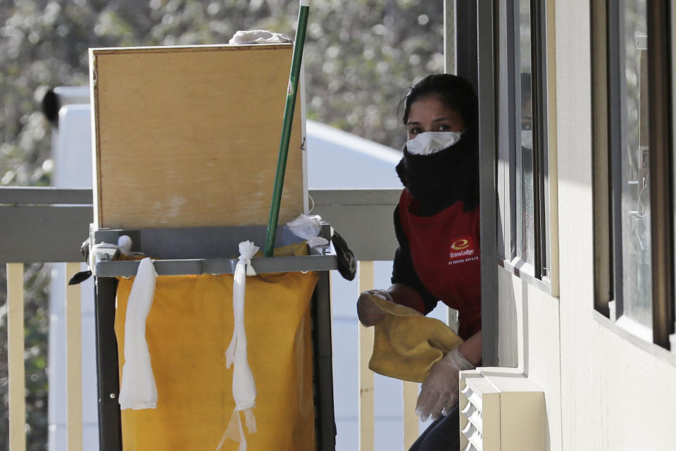A housekeeping worker wears a mask as she cleans a room, Wednesday, March 4, 2020, at an Econo Lodge motel in Kent, Wash. King County Executive Dow Constantine said Wednesday that the county had purchased the 85-bed motel south of Seattle to house patients for recovery and isolation due to the COVID-19 coronavirus. (AP Photo/Ted S. Warren)