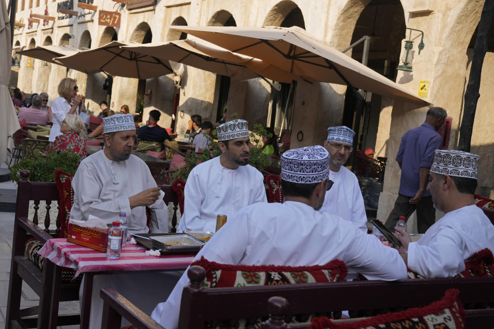 Omani supporters eat a meal at a restaurant at Souk Waqif before heading to watch the Asian Cup soccer match between Saudi Arabia and Oman, in Doha, Qatar, Tuesday, Jan. 16, 2024. (AP Photo/Aijaz Rahi)