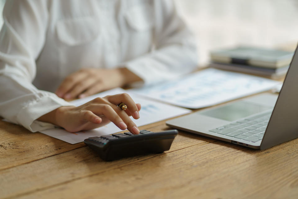 Close-up of business woman hand using a calculator to check company finances and earnings and budget