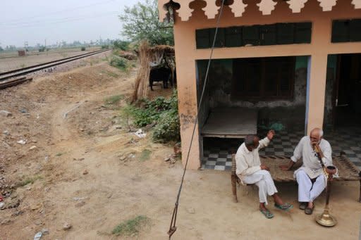 Two men sit near dried out fields in the village of Kherikhummar, in northern India in July 2012. India's economic growth could slip to near six percent this year with the country facing the spectre of its third drought in a decade, a top government policymaker says