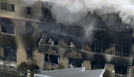 An aerial view shows firefighters battling the fires at the site where a man started a fire after spraying a liquid, at a three-story studio of Kyoto Animation Co. in Kyoto, western Japan, in this photo taken by Kyodo