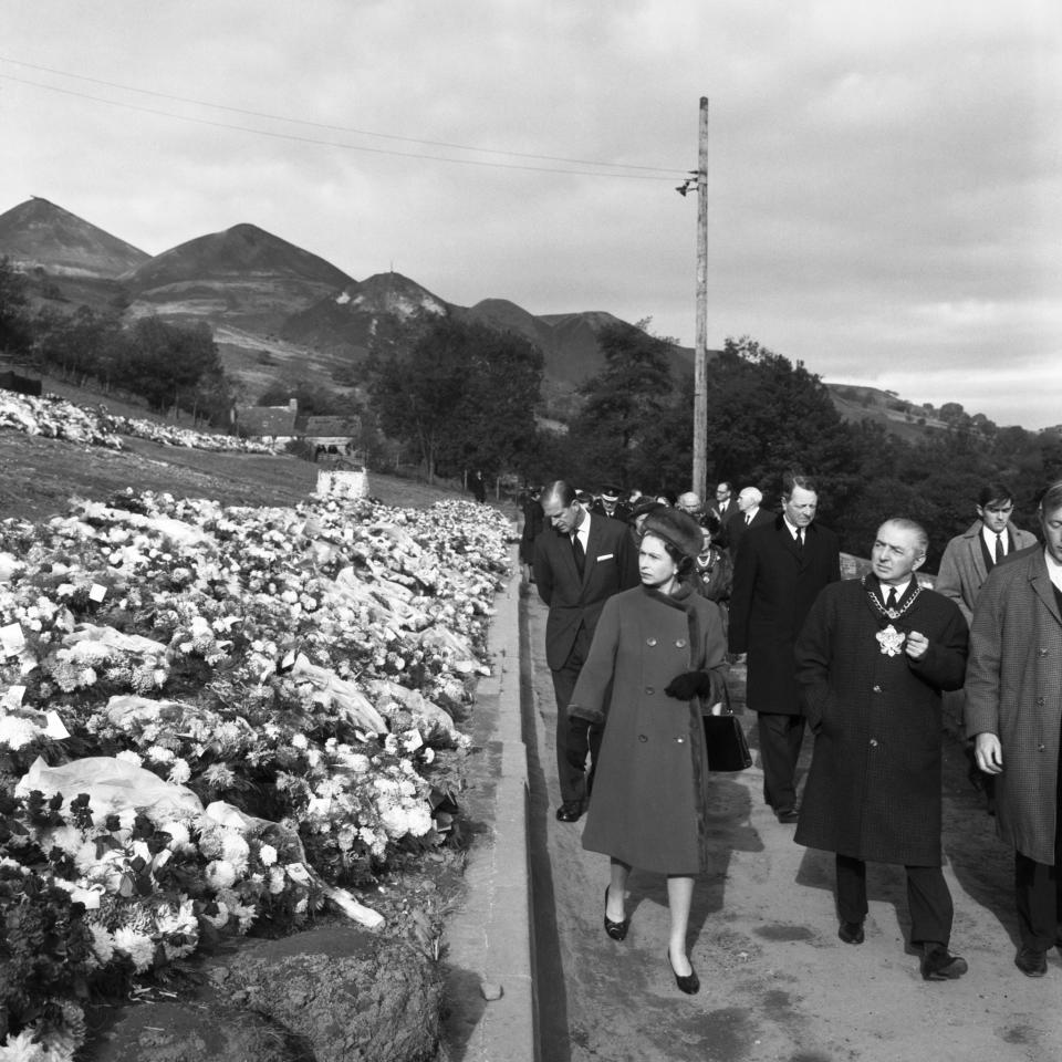 <p>The Duke of Edinburgh accompanies the Queen on a visit to the village of Aberfan, South Wales, to view a mass grave in the hillside cemetery of 82 of the 147 victims of the coal-tip avalanche. (PA Archive) </p>