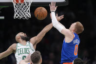 New York Knicks guard Donte DiVincenzo (0) shoots as Boston Celtics guard Derrick White (9) defends during the first half of an NBA basketball game Thursday, April 11, 2024, in Boston. (AP Photo/Steven Senne)
