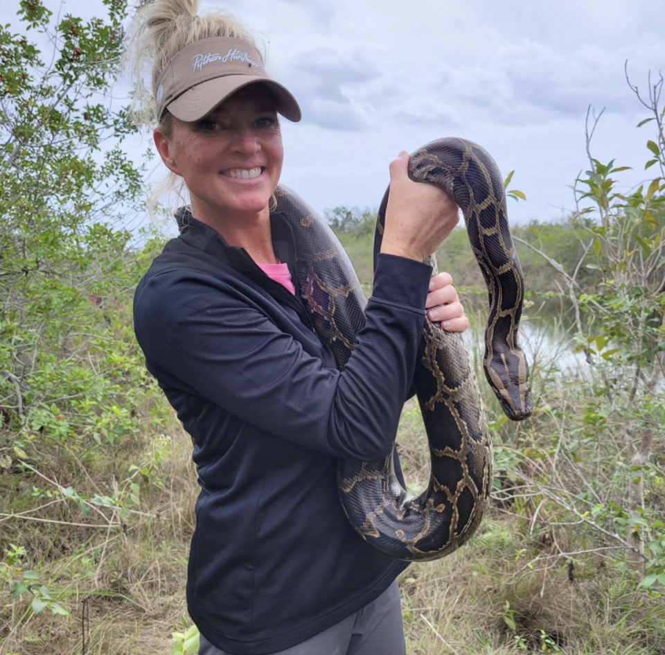 Amy Siewe, AKA the python huntress, poses with a 10-foot python she caught. Siewe removes the invasives to protect and preserve the Everglades.