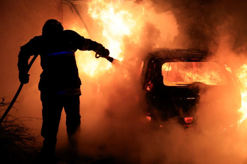 一輛汽車在1日晚間的暴亂遭縱火，消防隊員試圖撲滅火勢。路透社