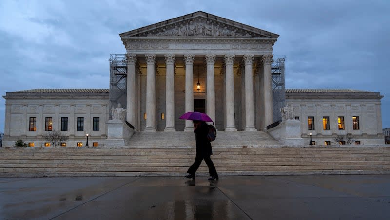 A woman under a purple umbrella walks past the Supreme Court, Wednesday, Feb. 28, 2024, in Washington. The Supreme Court agreed on Wednesday to decide whether former President Donald Trump can be prosecuted on charges he interfered with the 2020 election and has set a course for a quick resolution.