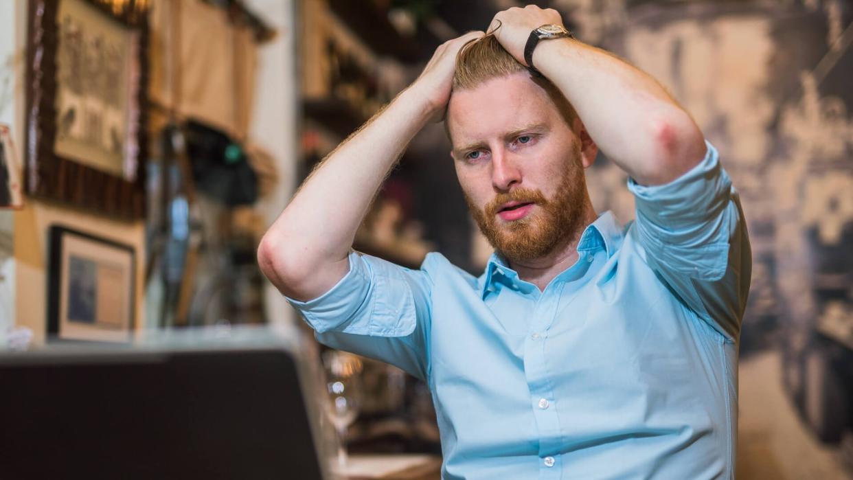 frustrated man looking at stocks tanking on his laptop