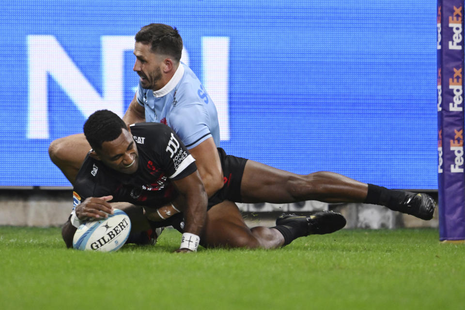Sevu Reece of the Crusaders, left, scores a try despite pressure from Jake Gordon of the Waratahs during their Super Rugby Pacific Round 8 match in Sydney, Friday, April 12, 2024. (Dean Lewins/AAP Image via AP)