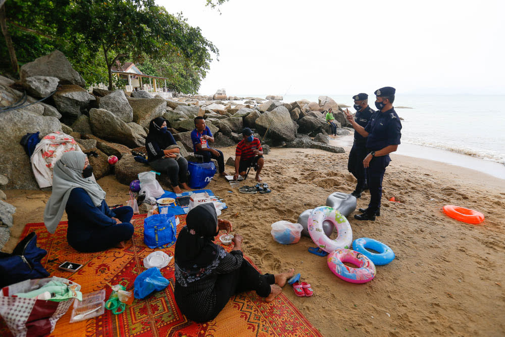 Penang CPO Datuk Mohd Suhaily Mohd Zain (left) along with North-east District Police Chief ACP Soffian Santong speak to beachgoers during the public holiday at Shamrock Beach, Batu Ferringhi, September 16, 2021. — Picture by Sayuti Zainudin