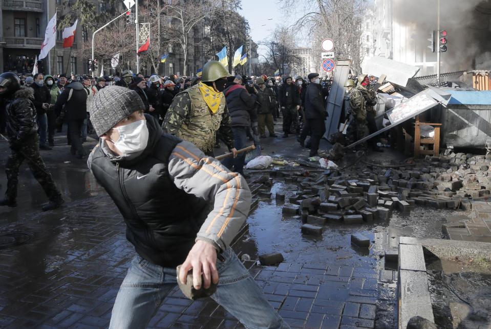 Anti-government protesters lob stones during clashes with riot police outside Ukraine's parliament in Kiev, Ukraine, Tuesday, Feb. 18, 2014. Some thousands of angry anti-government protesters clashed with police in a new eruption of violence Tuesday. (AP Photo/Efrem Lukatsky)