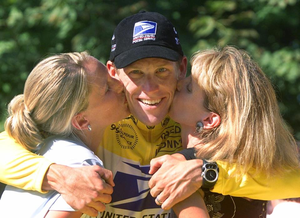 FILE - This July 25, 1999 file photo shows Tour de France winner Lance Armstrong being kissed by his wife Kristin, left, and his mother Linda after the 20th and final stage of the Tour de France cycling race in Paris. The superstar cyclist, whose stirring victories after his comeback from cancer helped him transcend sports, chose not to pursue arbitration in the drug case brought against him by the U.S. Anti-Doping Agency. That was his last option in his bitter fight with USADA and his decision set the stage for the titles to be stripped and his name to be all but wiped from the record books of the sport he once ruled. (AP Photo/Laurent Rebours, File)