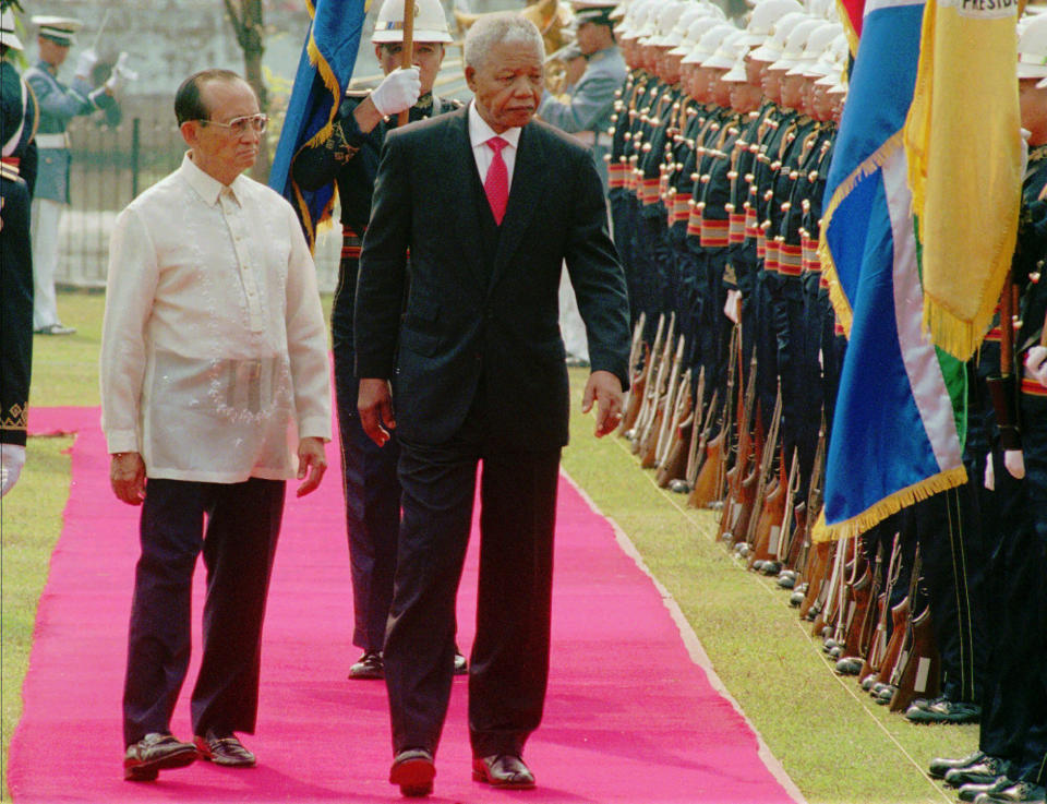 FILE - Philippine President Fidel Ramos, left, escorts South African President Nelson Mandela as they review an honor guard on March 1, 1997, at the Malacanang palace in Manila. Ramos, a U.S.-trained ex-general who saw action in the Korean and Vietnam wars and played a key role in a 1986 pro-democracy uprising that ousted a dictator, has died. He was 94. Some of Ramos's relatives were with him when he died on Sunday, July 31, 2022, said his longtime aide Norman Legaspi. (AP Photo/Pat Roque, File)