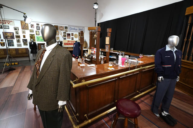 The bar used on the set of the television series "Cheers" and some costumes worn by actors on the sitcom are shown, Thursday, April 27, 2023, in Irving, Texas. A dizzying number of props, sets, and costumes from television shows beloved by generations of viewers will be sold at auction next month. The collection James Comisar has spent over 30 years amassing includes "The Tonight Show" set Johnny Carson gave him after retiring, the timeworn living room from "All in the Family," and the bar where Sam Malone served customers on Cheers. (AP Photo/Tony Gutierrez)