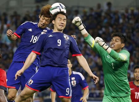 Singapore's goalkeeper Izwan Mahbud (R) fights for the ball with Japan's Shinji Okazaki (C) and Yuya Osako during their 2018 World Cup qualifying soccer match at Saitama Stadium in Saitama, north of Tokyo June 16, 2015. REUTERS/Issei Kato