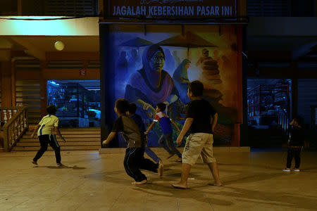 Children play football by a mural at Pasar Siti Khadijah in Kota Bharu, Kelantan, Malaysia April 11, 2018. REUTERS/Stringer