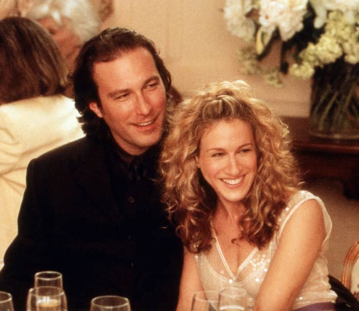 Aidan and Carrie smiling as they sit together at a dinner