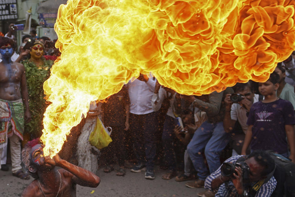 An artist performs a fire stunt during a procession marking "Bonalu" festival in Hyderabad, India, Monday, July 17, 2023. Bonalu is a month-long Hindu folk festival dedicated to Kali, the Hindu goddess of destruction. (AP Photo/Mahesh Kumar A.)