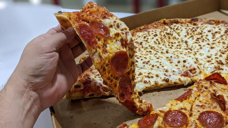 holding slice of costco pizza