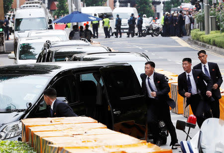 North Korean security personnel run next to a motorcade believed to be carrying North Korea's leader Kim Jong Un in Singapore June 10, 2018, ahead of the summit between the North Korean leader and U.S. President Donald Trump. REUTERS/Tyrone Siu