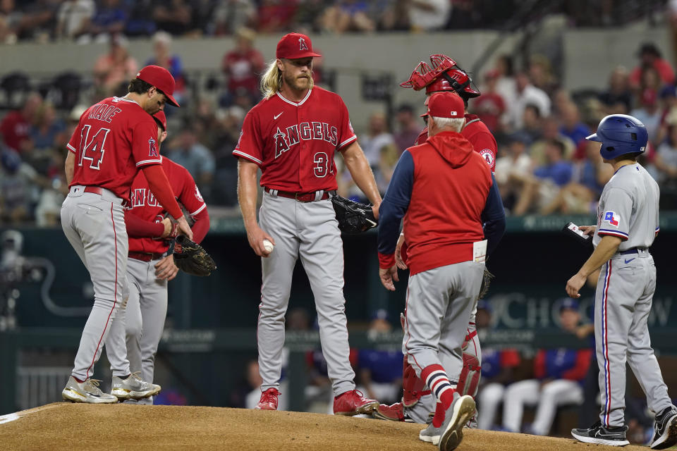 Los Angeles Angels starting pitcher Noah Syndergaard (34) stands on the mound with teammates as manager Joe Maddon heads out to make a pitching change during the first inning of a baseball game against the Texas Rangers in Arlington, Texas, Monday, May 16, 2022. (AP Photo/LM Otero)