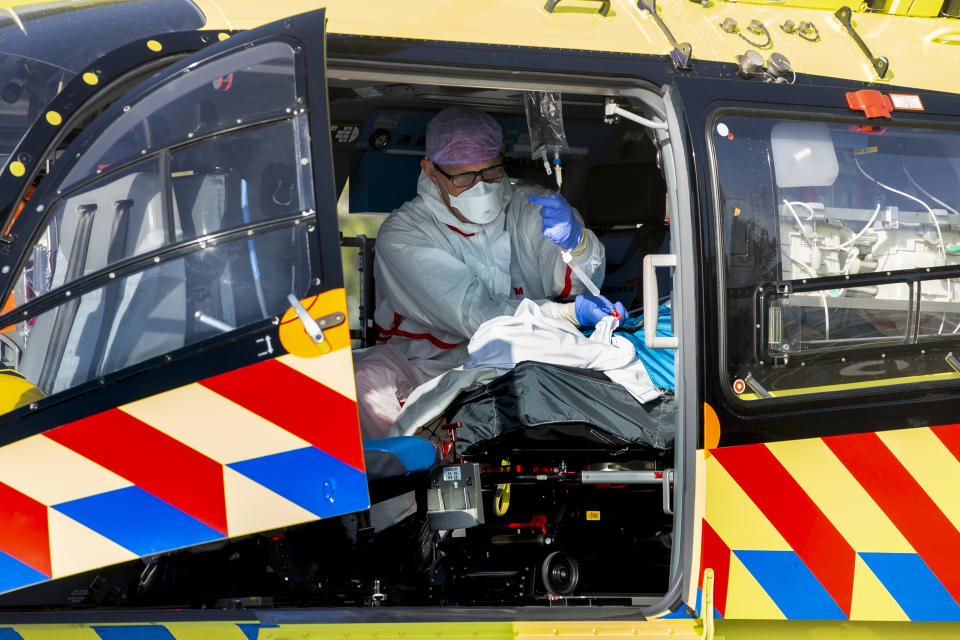 A COVID-19 patient is being tended to prior to being airlifted with the helicopter from FlevoZiekenhuis, or FlevoHospital, in Almere, Netherlands, Friday, Oct. 23, 2020. In the latest sign of the scale of the coronavirus pandemic sweeping across Europe, a helicopter started airlifting COVID-19 patients from the Netherlands to an intensive care unit in the German city of Muenster.(AP Photo/Peter Dejong)