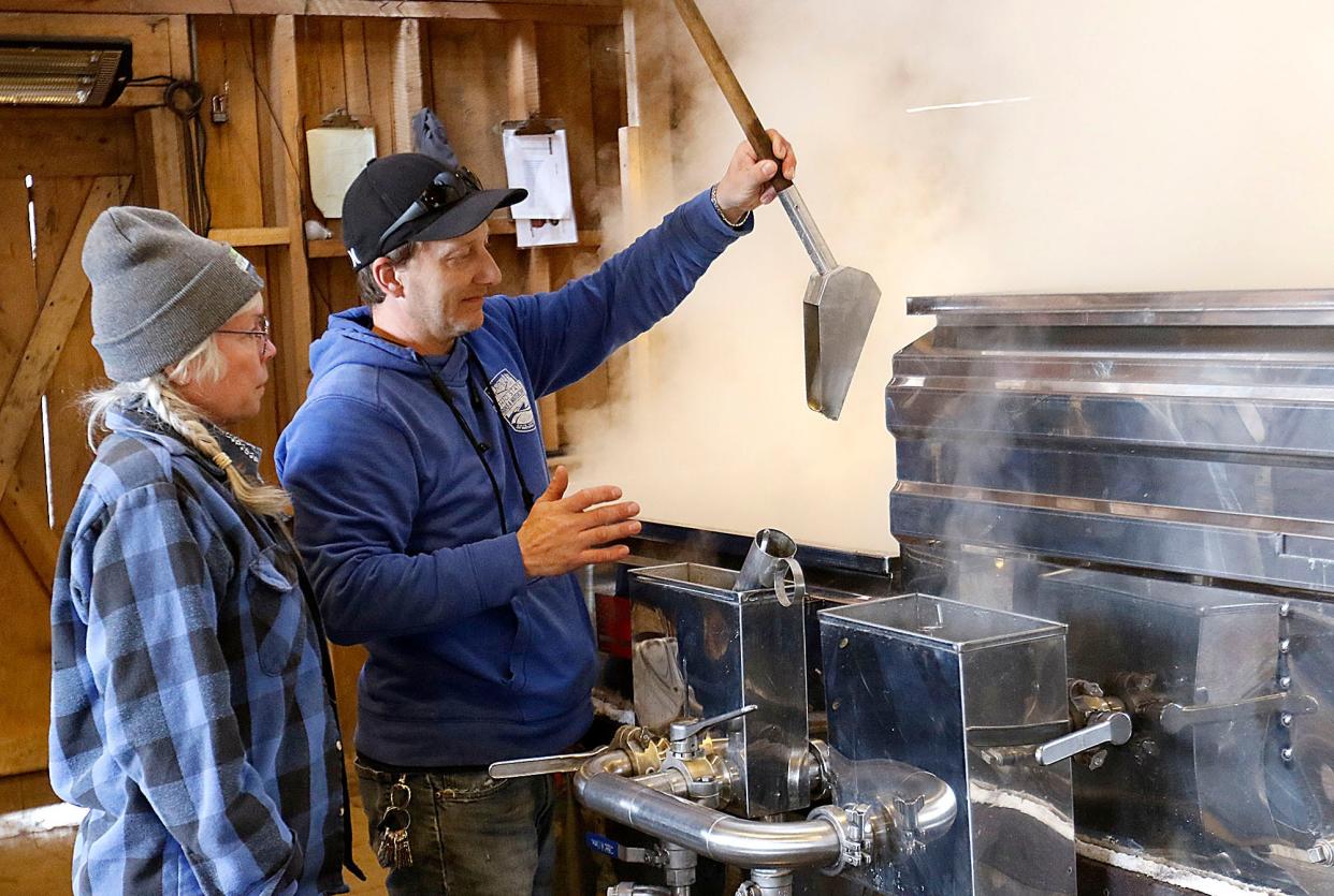 Kiristin Brubach and Jon Britton check the progress of the maple syrup as they boil it to extract the maple syrup in the Malabar Farm Sugar Shack Tuesday, Feb. 21, 2023. TOM E. PUSKAR/ASHLAND TIMES-GAZETTE