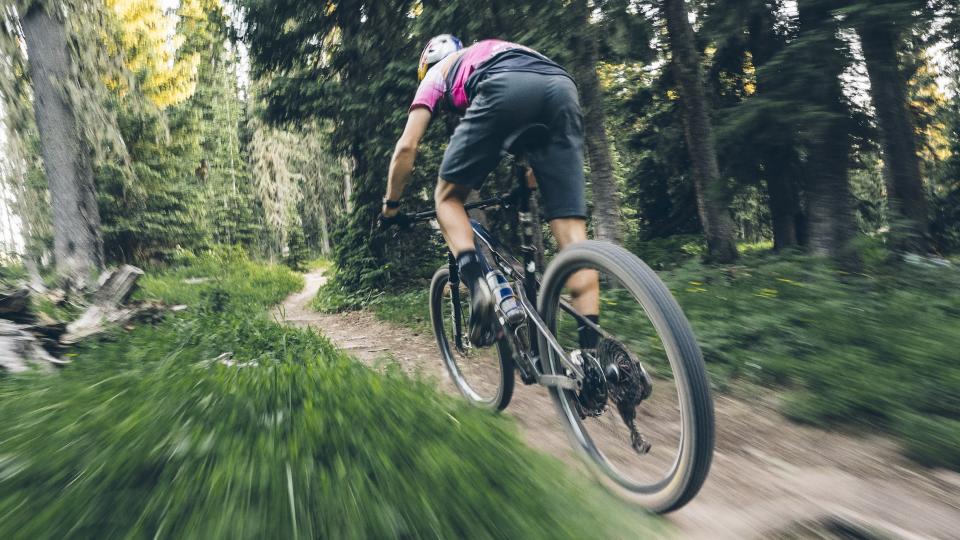  Man rapidly riding a mountain bike on a trail. 