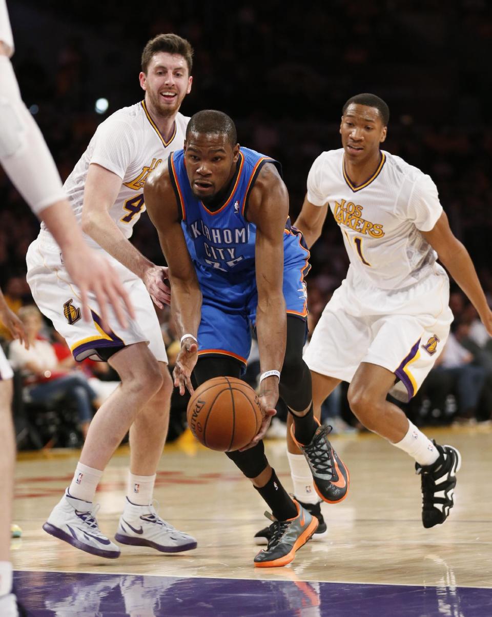 Oklahoma City Thunder small forward Kevin Durant, center, takes the ball between Los Angeles Lakers power forward Ryan Kelly, left, and small forward Wesley Johnson, right, during the first half of an NBA basketball game in Los Angeles, Sunday, March 9, 2014. (AP Photo/Danny Moloshok)