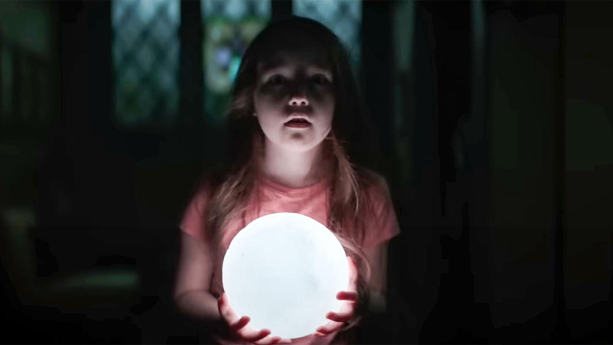  A girl holds a light in a dark room. 