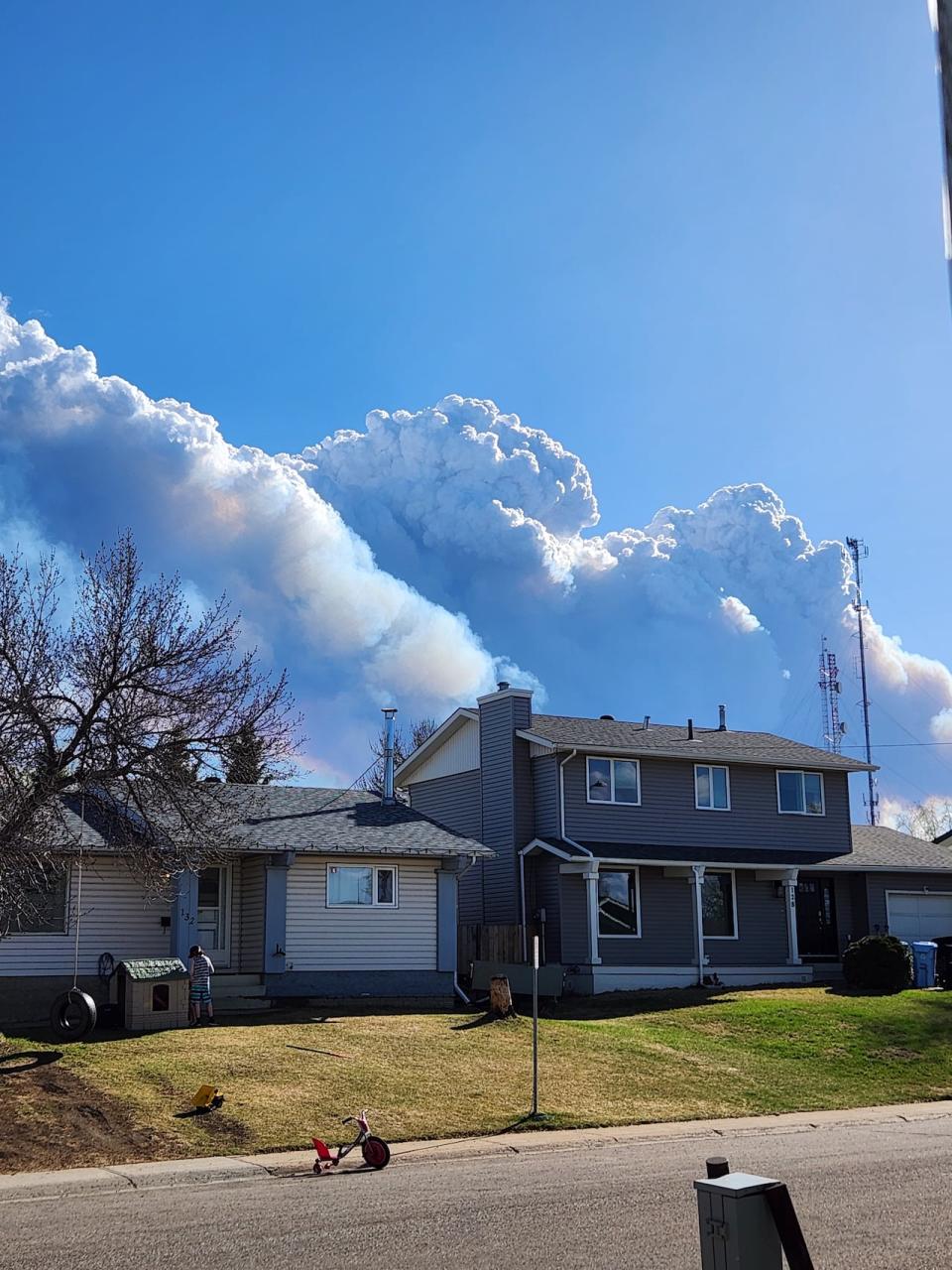 Plumes of smoke rise behind a house in Fort McMurray, Alta. 