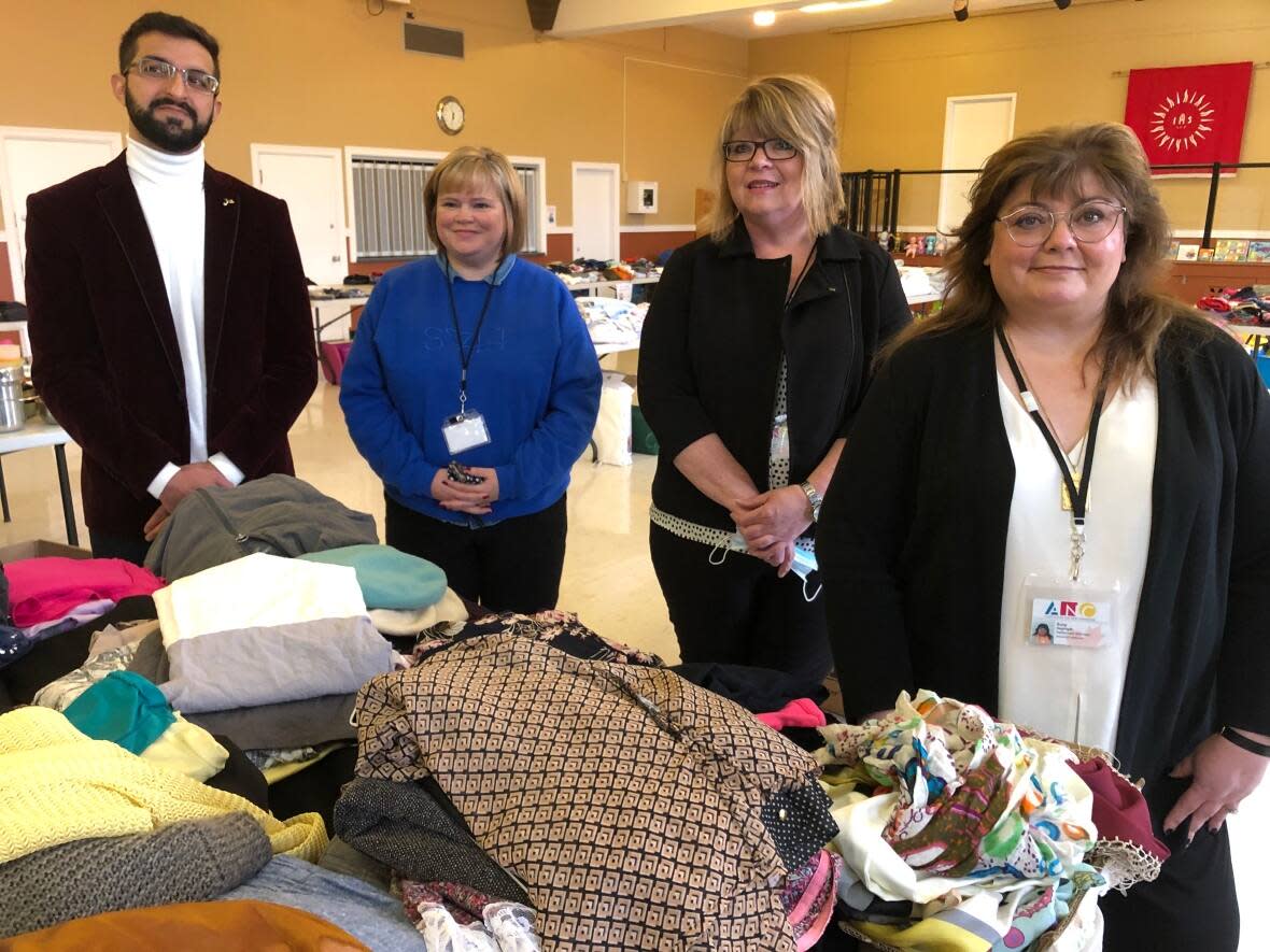 The ANC's Antwone Aslan, Alice Keough, Megan Morris and Suzy Haghighi pose for pictures in front of some of the donations the group has received for the new comers. (Jeremy Eaton/CBC - image credit)