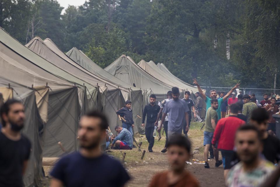 Migrants walk inside the newly built refugee camp in the Rudninkai military training ground, some 38km (23,6 miles) south from Vilnius, Lithuania, Wednesday, Aug. 4, 2021. The Red Cross warned Wednesday that Lithuania's decision to turn away immigrants attempting to cross in from neighboring Belarus does not comply with international law. Lithuania, a member of the European Union, has faced a surge of mostly Iraqi migrants in the past few months. Some 4,090 migrants, most of them from Iraq, have crossed this year from Belarus into Lithuania. (AP Photo/Mindaugas Kulbis)